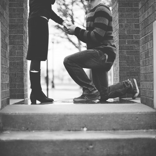 A man on one knee proposing to a woman