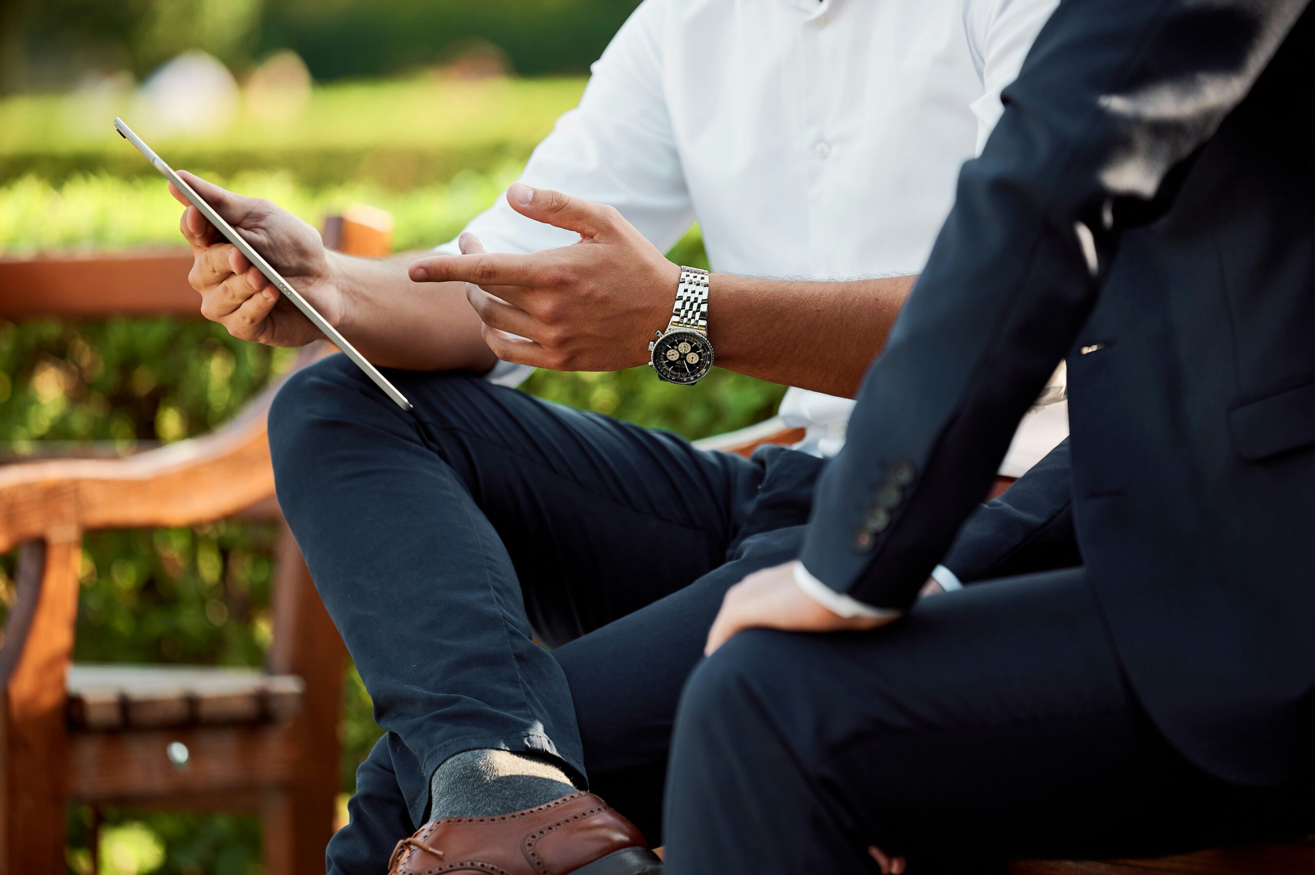 Two men sitting on a bench looking at a tablet, representing financial services, banking law, and fintech legal solutions by the Vancouver lawyers at EKB law firm
